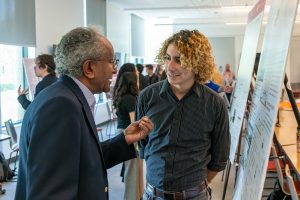 Student Hasan Cruz speaking with WSU professor in front of his research poster.