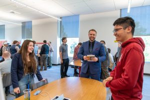 Two students smiling with a judge from PNNL as they review their research poster.