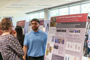 Student presenting a research poster titled "Birds in the Vineyards: Friends or Foes?" to a faculty member.