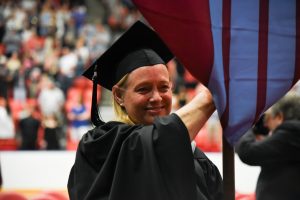 Becky Rausch carries the College of Education gonfalon banner during the 2018 WSU Tri-Cities commencement ceremony