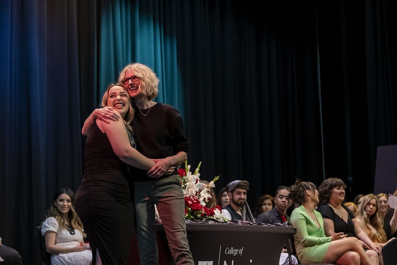nursing student hugs faculty member on stage
