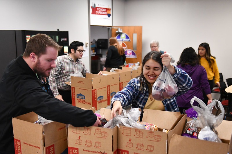 Students and staff placing food in cardboard boxes lined up outside of the WSU Tri-Cities Cougar Cupboard.