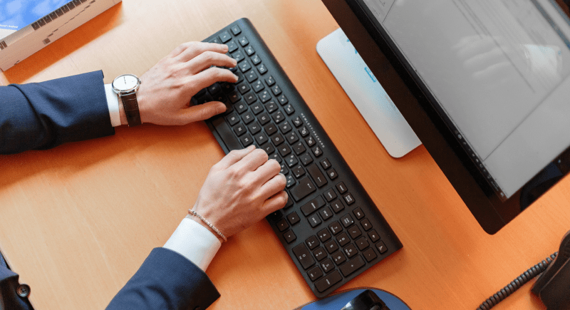 Man typing on a keyboard while using a computer