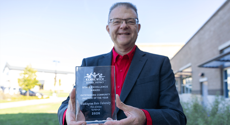 John Mancinelli holding a Staff Excellence Award from Kennewick School District for Outstanding Community Partner of the Year 2026.