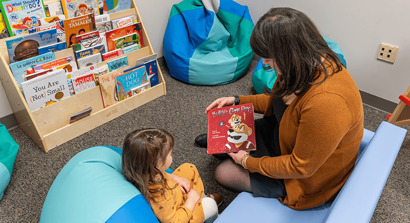 Woman reading a book to a child titled "Butch's Game Day".