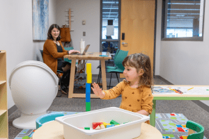 Evelyn Martinez-Ostrom watching as her daughter stacks blocks into a tower.