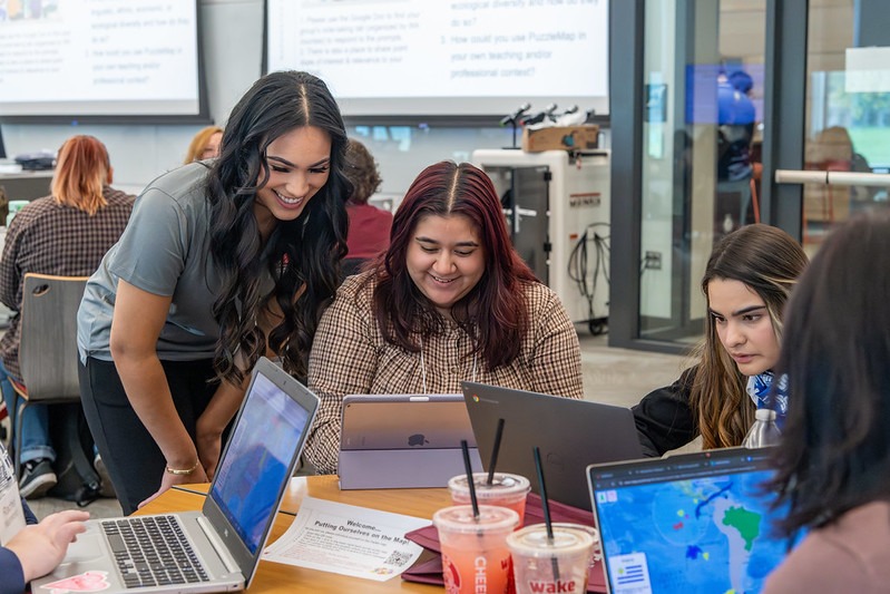 Two WSU Tri-Cities students looking at a laptop and smiling.
