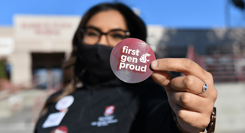 Person holding sticker that reads "first gen proud".