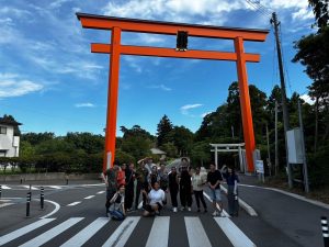 A group of students standing under a large red shrine gate.