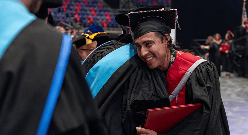 Jesus Delgado Sholtys hugging a faculty member at commencement.