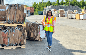 Maria Paula Garcia-Tovar standing next to stacks of cardboard at a recycling center.