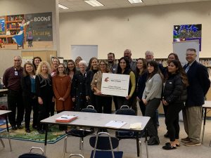 Teachers from Maya Angelou Elementary and leadership from WSU Tri-Cities, and the Pasco School District stand with the sign identifying Maya Angelou Elementary as a WSU Tri-Cities College of Education Laboratory School.