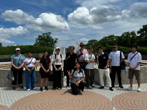 A group of students standing in front of the Nagasaki Peace Fountain.