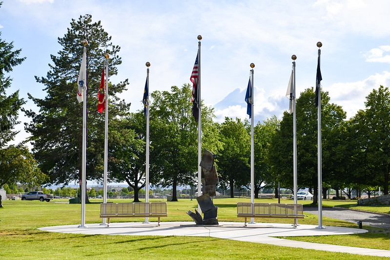 Sculpture of pages lifting to the sky surrounded by flags.