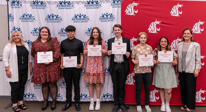 Students standing with certificates in front of KSD and WSU backdrops