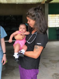 Kenzie McNeel holds an infant while completing her a clinical rotation at a remote village in Peru.