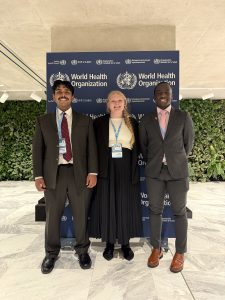 Bhargav Iyer, Zoe Pfeifer, and Romeo Ross standing in front of a sign that reads, World Health Organization.