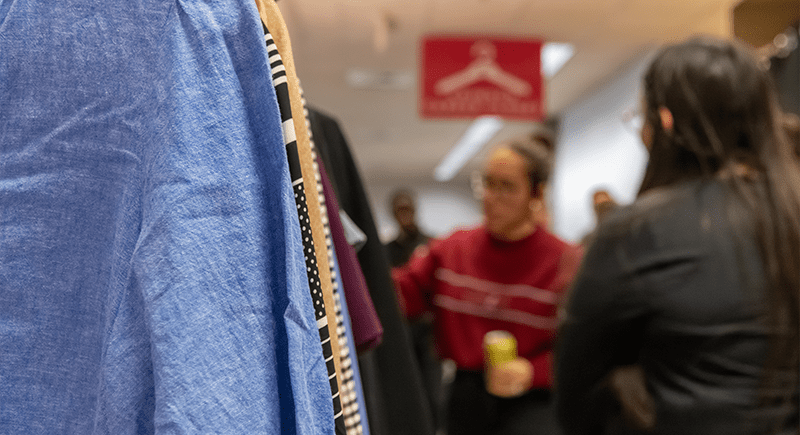 Shirts on a clothes rack, with people out of focus in the background.