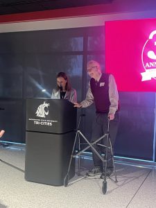 Chancellor Sandra Haynes and Jim Cochran standing behind a podium with the WSU Tri-Cities logo on it.