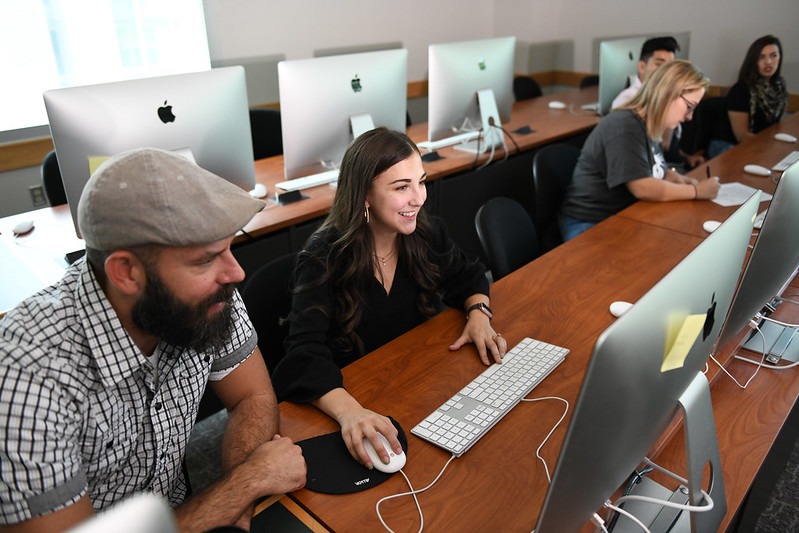 WSU Tri-Cities professor helping a student working on a Mac computer.