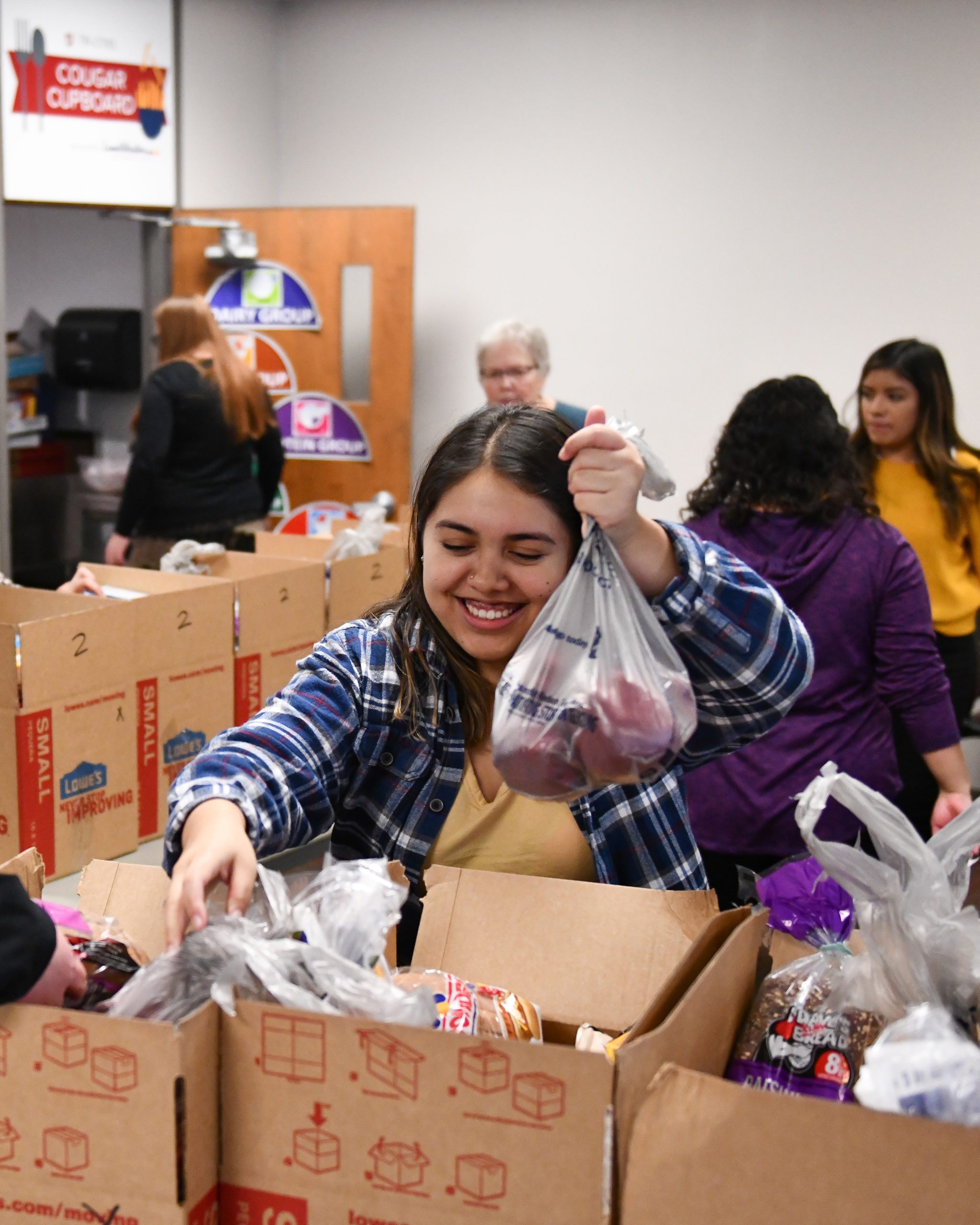 Student volunteers filling cardboard boxes with bread and fresh produce.