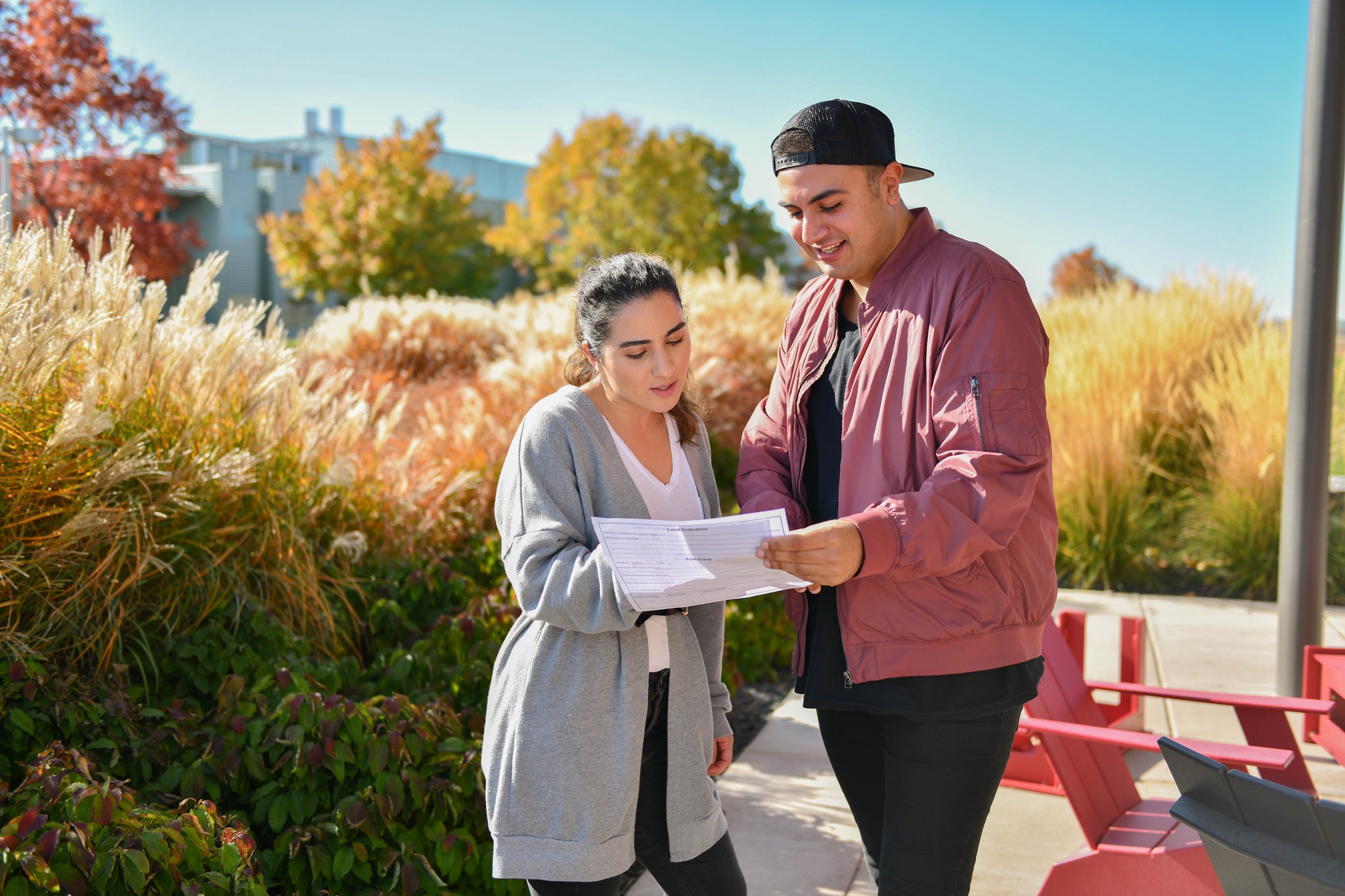 Two students standing outside looking down at a piece of paper.