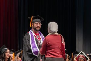 Dakota Levine and Professor Ameera Fayad shaking hands on stage.