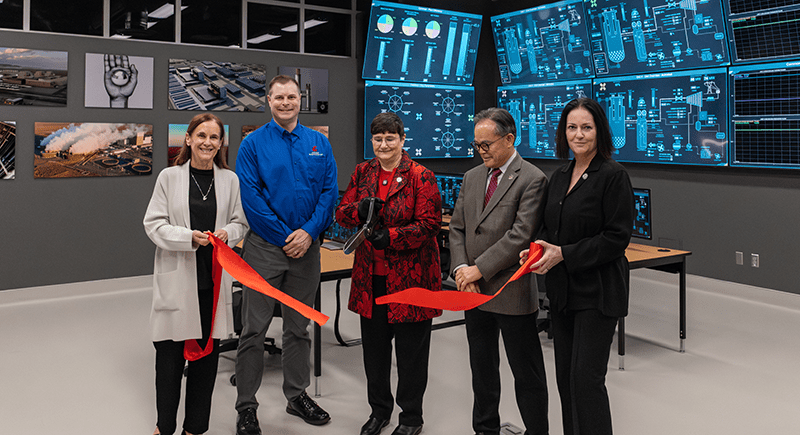 WSU staff cutting red ribbon in front of nuclear reactor simulator.