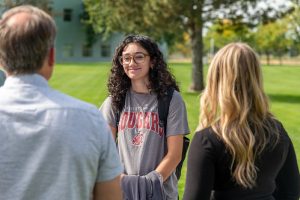 A student speaks to two H2C representatives outside by a campus lawn.