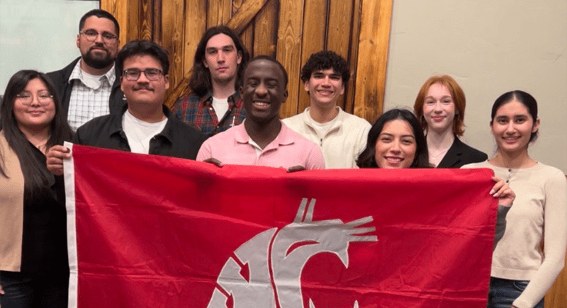 A group of students holding a large crimson WSU flag.