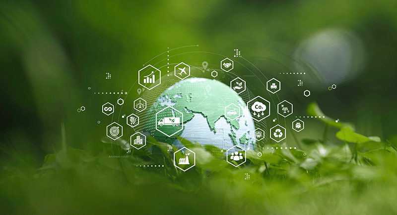 Globe resting in green grass, overlaid with white icons representing sustainable logistics and environmental concepts such as renewable energy, recycling, transportation, CO₂ reduction, and global connectivity.