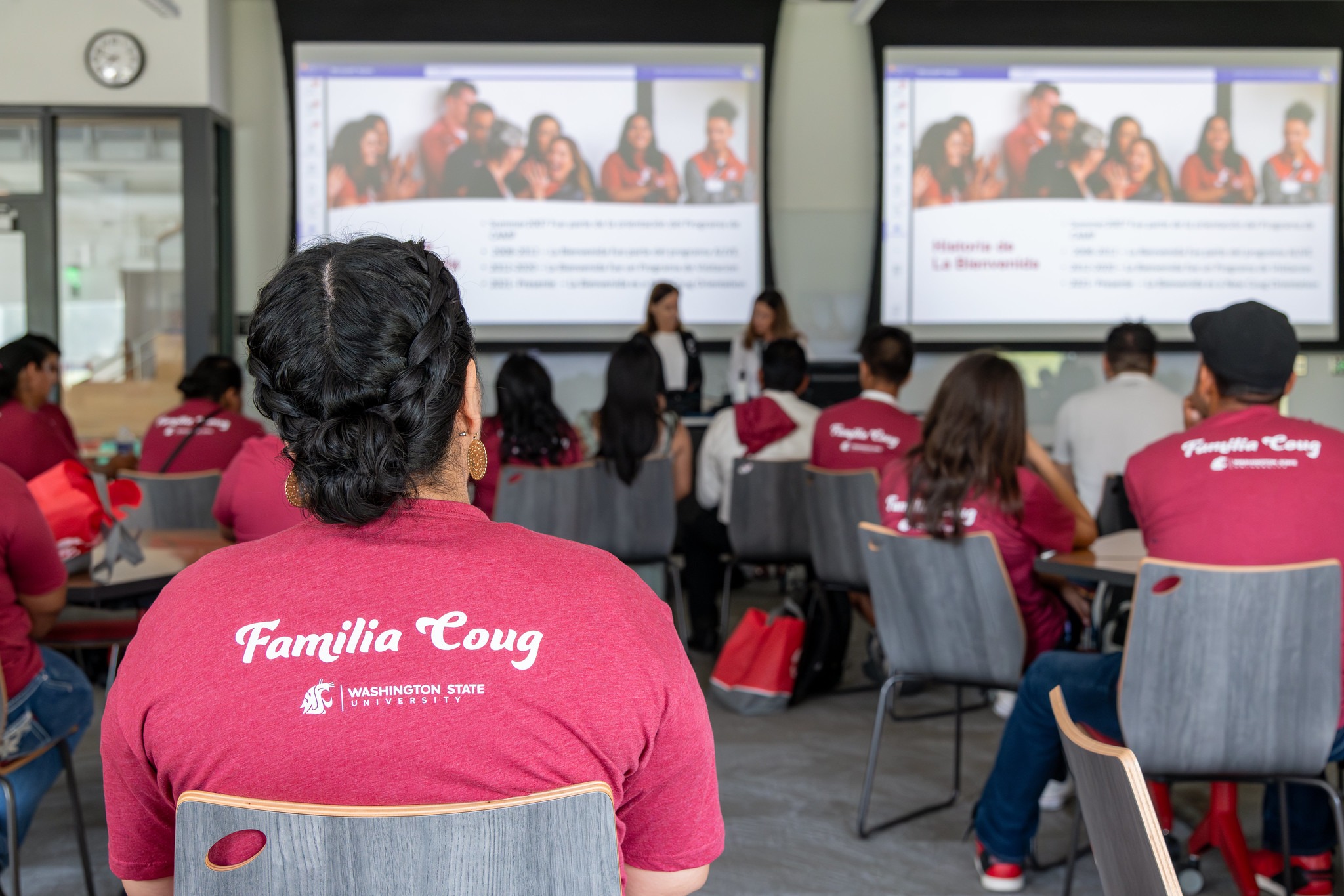 Student seated watching a presentation with a shirt that reads, Familia Coug.