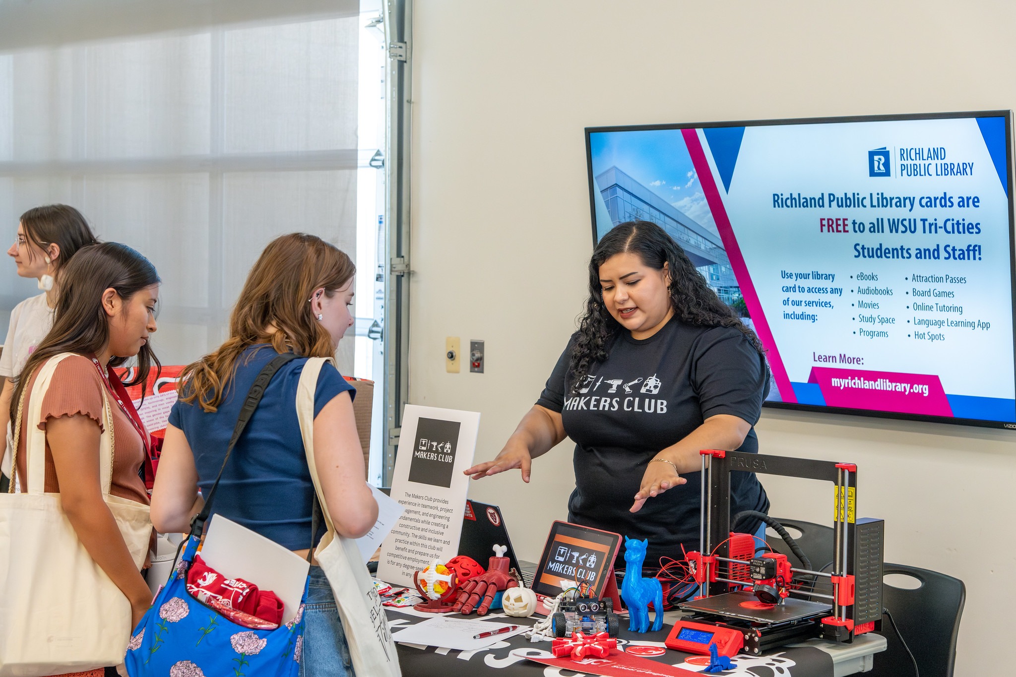 Makers Club student showing equipment to two students.