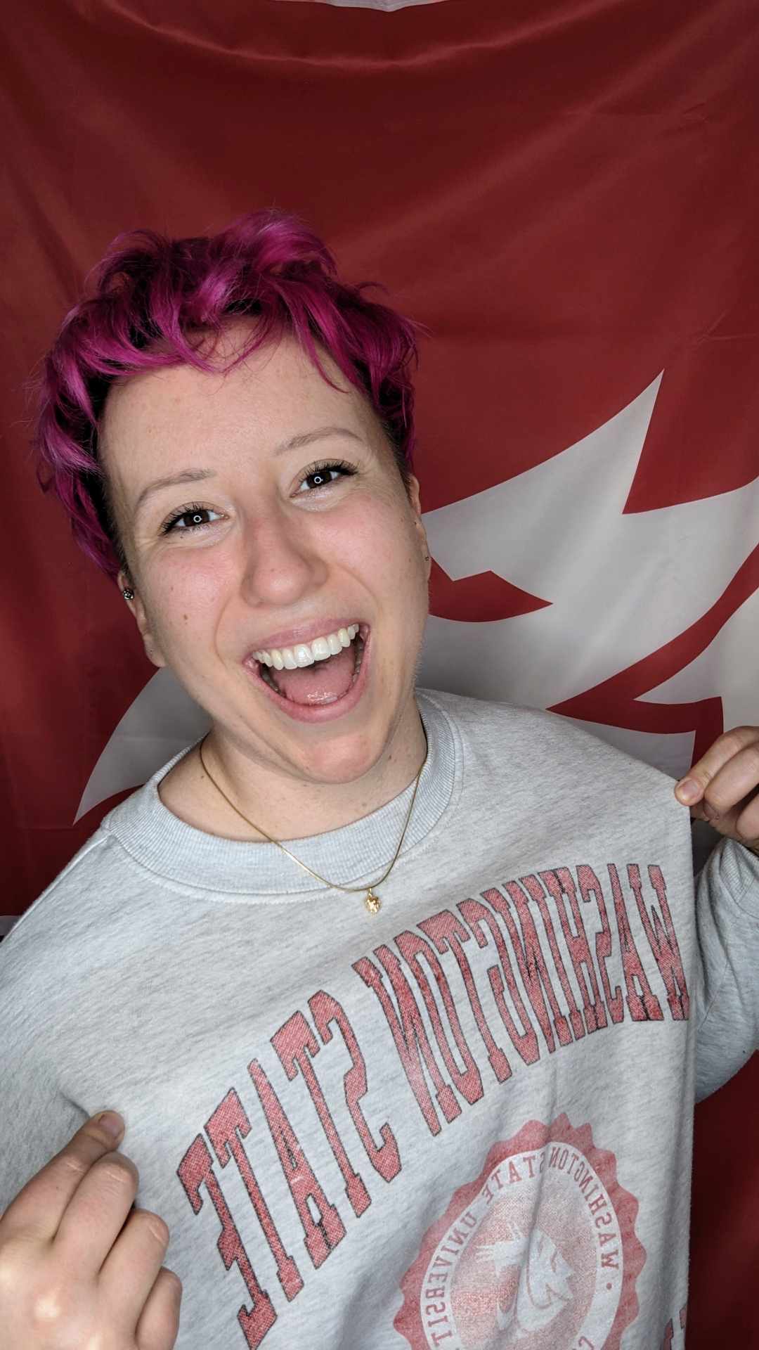 Madison Rosenbaum in front of a Coug flag wearing a WSU sweater